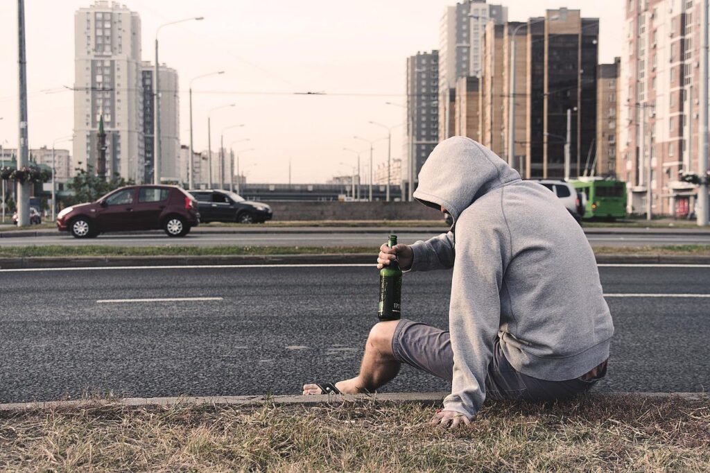 道路わきで酒を飲んでうなだれる男性