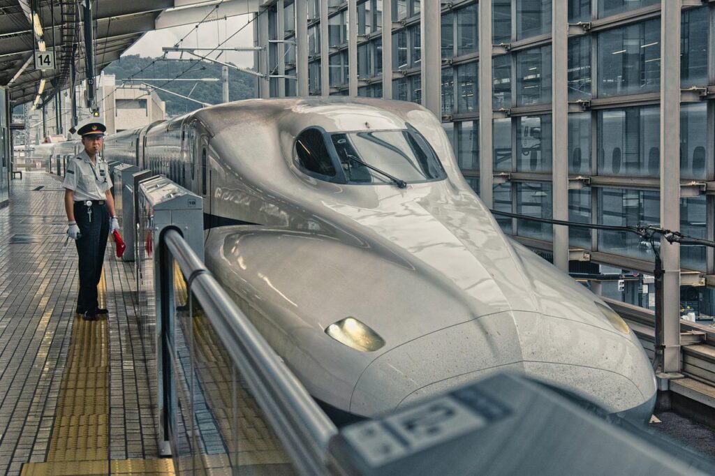 ピカピカの新幹線と発車を見守る駅員さん